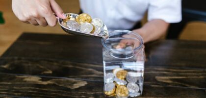 a man putting coins in a jar - GIBX Stock News